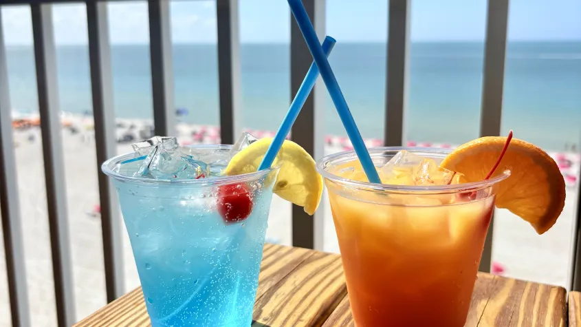 tropical drinks on a wooden table top overlooking the beach
