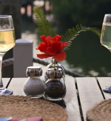Two wine glasses sit tableside to a canal on Fort Myers Beach at sunset