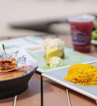 A variety of plated food and drinks on a table waterfront at the Boat House in Fort Myers