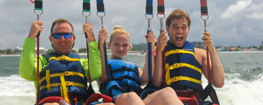 Teens and their dad enjoy a parasailing adventure.