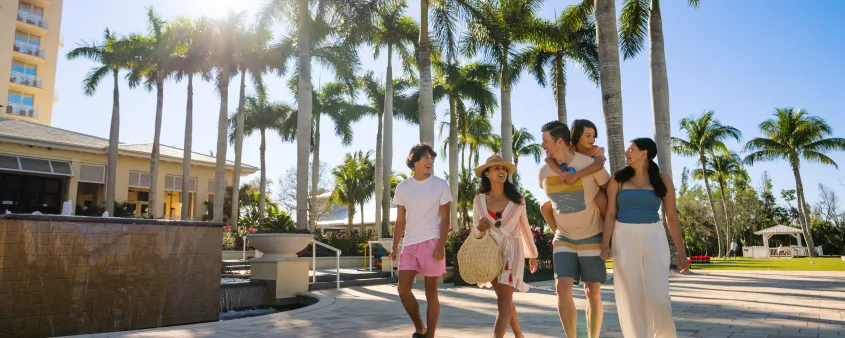 A family walks beneath palm trees outside Hyatt Regency Coconut Point Resort and Spa in Bonita Springs.