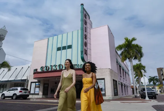 Two women stand outside the pink Art Deco facade of the Edison Theatre downtown.