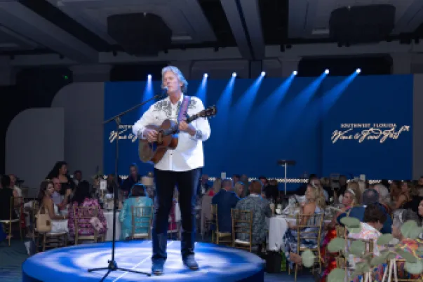 Event photography of a man singing onstage while playing guitar.